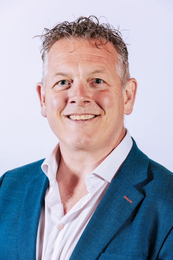 qualtrics-WhatsApp-Image-2024-06-06-at-13.41.4 Smiling man in a blue suit.